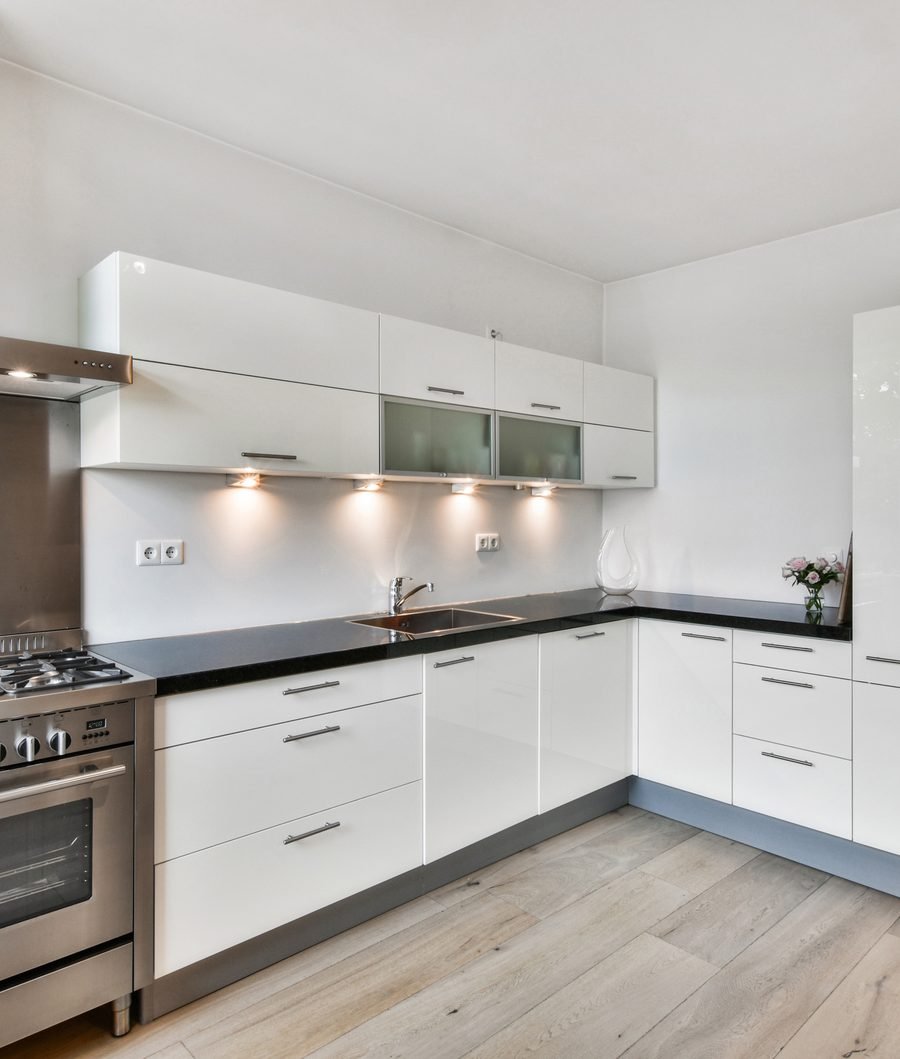White modular kitchen with black countertops and stainless steel appliances